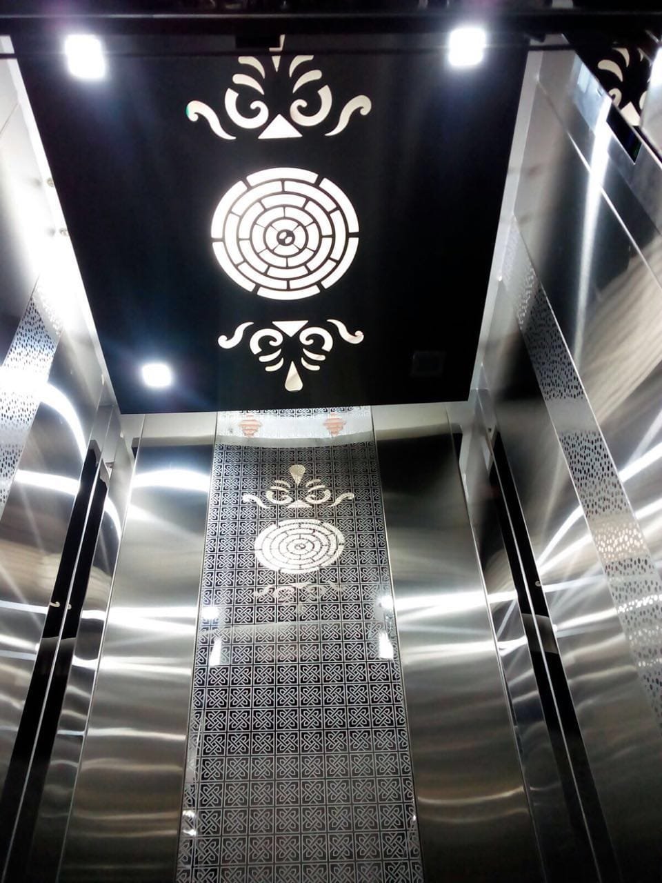 Modern passenger elevator cabin with stainless steel interior and decorative ceiling design